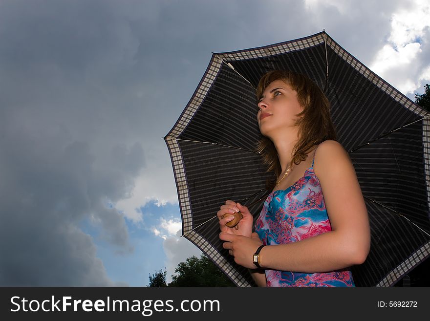 Girl under a umbrella on a background of the sky with clouds