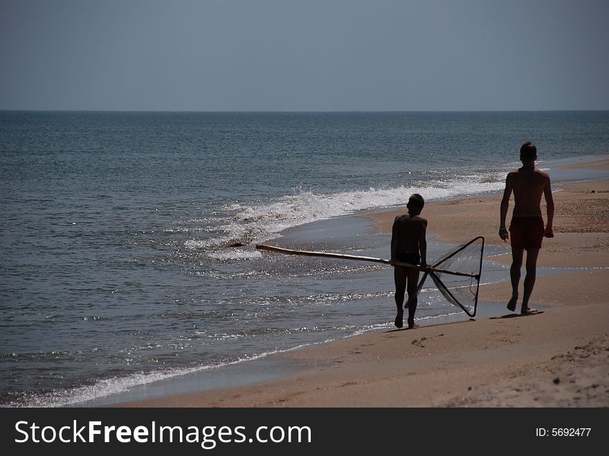 Boys silhouettes fishing on the beach. Boys silhouettes fishing on the beach