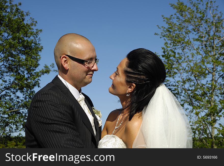 Bride and groom are standing close together looking at each other.