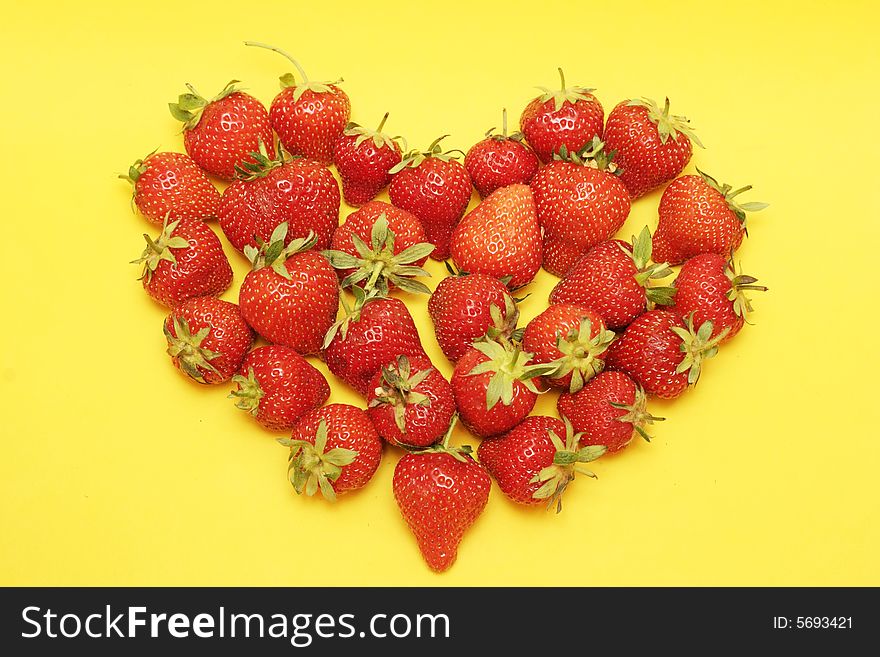 Strawberries on a yellow background in shape of a heart. Strawberries on a yellow background in shape of a heart