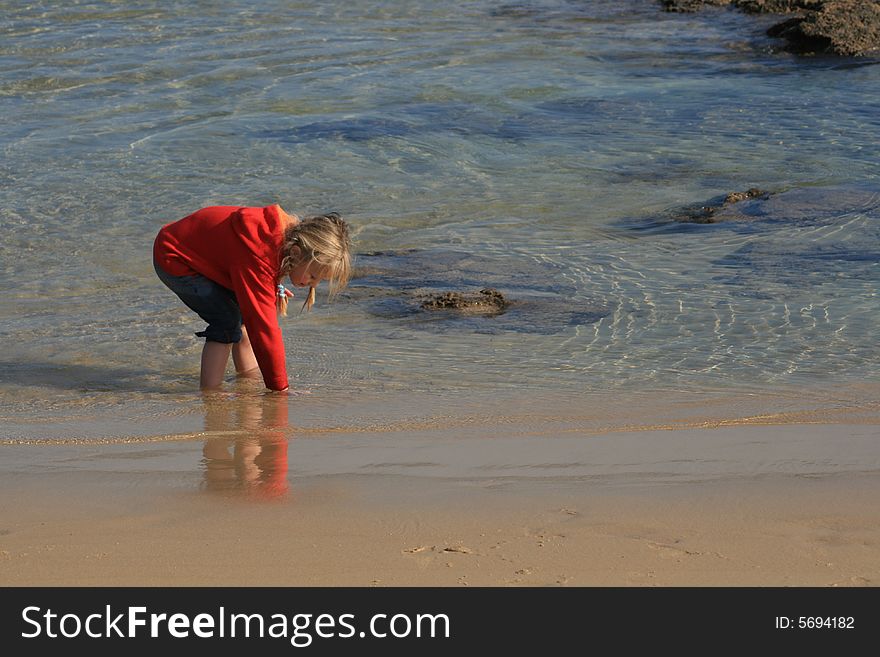 A beautiful white caucasian girl child playing in the water at the beach. A beautiful white caucasian girl child playing in the water at the beach