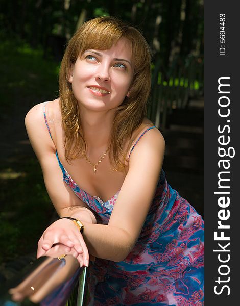 Beautiful girl stands having leaned on a steel handrail