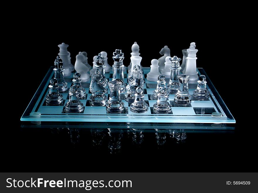 Chessboard and chess pieces made of glass against a black background