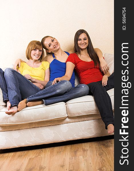 Three young beautiful women are sitting on a lounge. Three young beautiful women are sitting on a lounge