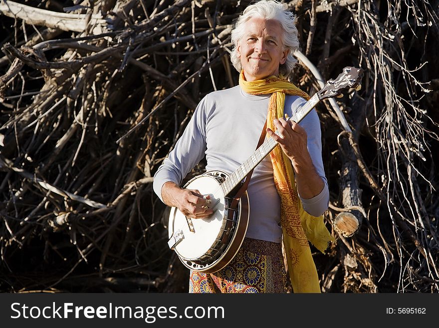 Banjo Player in Front of a Big Pile of Wood