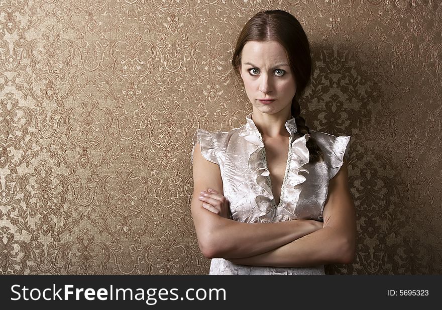 Pretty young woman waiting leaning up against a wall with gold wallpaper. Pretty young woman waiting leaning up against a wall with gold wallpaper