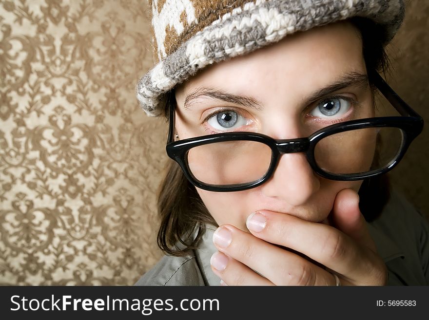 Closeup of Cute Nerdy Woman in a Knit Cap Covering Her Face With Her Hand