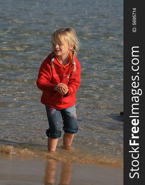 A beautiful white caucasian girl child playing in the water at the beach. A beautiful white caucasian girl child playing in the water at the beach