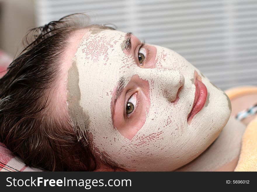 The brunette in a clay cosmetic mask. The brunette in a clay cosmetic mask
