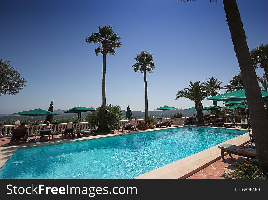 Poolside at bormes les mimosas, french riviera, france, waves, lounge chair, parasol  and palm tree. Poolside at bormes les mimosas, french riviera, france, waves, lounge chair, parasol  and palm tree