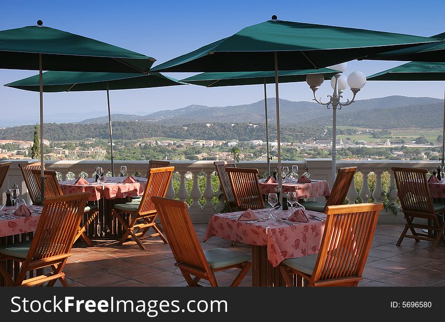 Restaurant table towels and glasses on sunny terrace french riviera balcony and parasols. Restaurant table towels and glasses on sunny terrace french riviera balcony and parasols