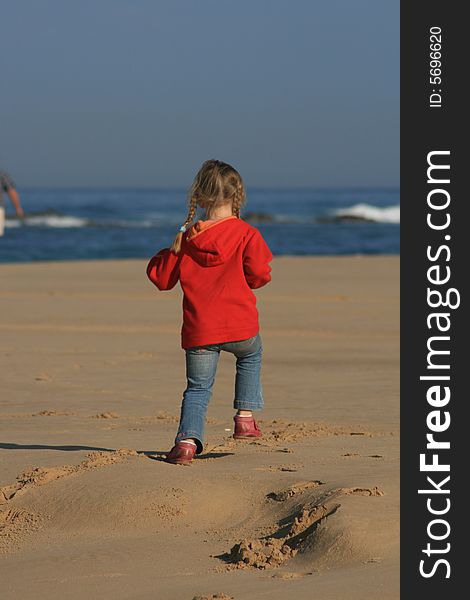 A beautiful white caucasian girl child running freely on the beach having fun. A beautiful white caucasian girl child running freely on the beach having fun