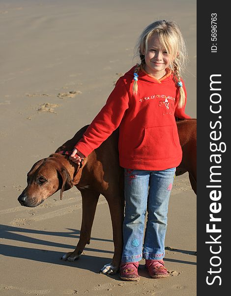 A beautiful white caucasian girl child with her dog on the beach. A beautiful white caucasian girl child with her dog on the beach