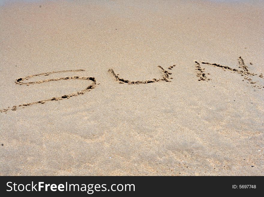 A sandy beach with the word SUN written in sand