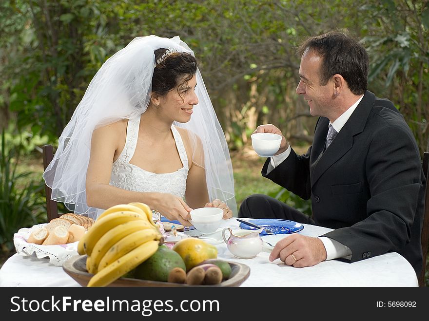 A newly married couple, sitting at a table smiling and gazing at each other - horizontally framed. A newly married couple, sitting at a table smiling and gazing at each other - horizontally framed