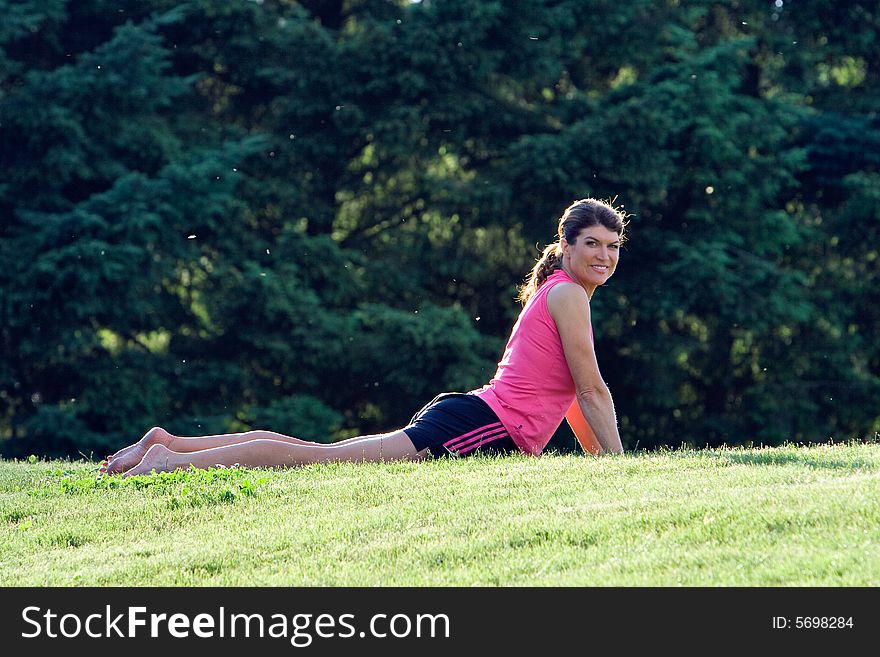 A woman, lying in the grass, stretches her back, smiling - horizontally framed. A woman, lying in the grass, stretches her back, smiling - horizontally framed