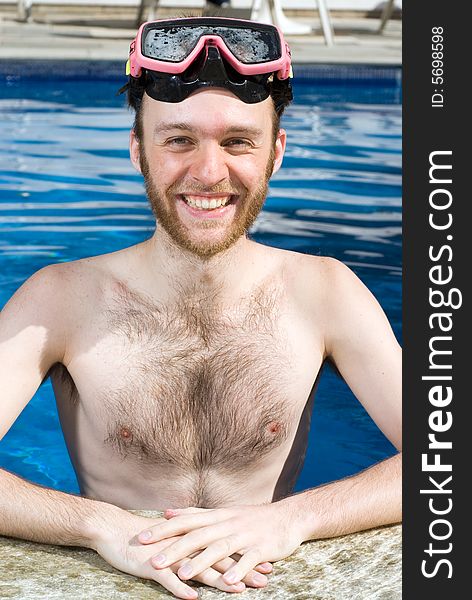A Man is standing in a pool. He is smiling and looking at the camera. He is wearing goggles. Vertically framed photo. A Man is standing in a pool. He is smiling and looking at the camera. He is wearing goggles. Vertically framed photo.