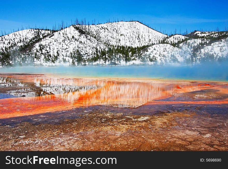 Snowy hills behind the colorful Grand Prismatic Spring (Midway Geyser Basin) - Yellowstone National Park.