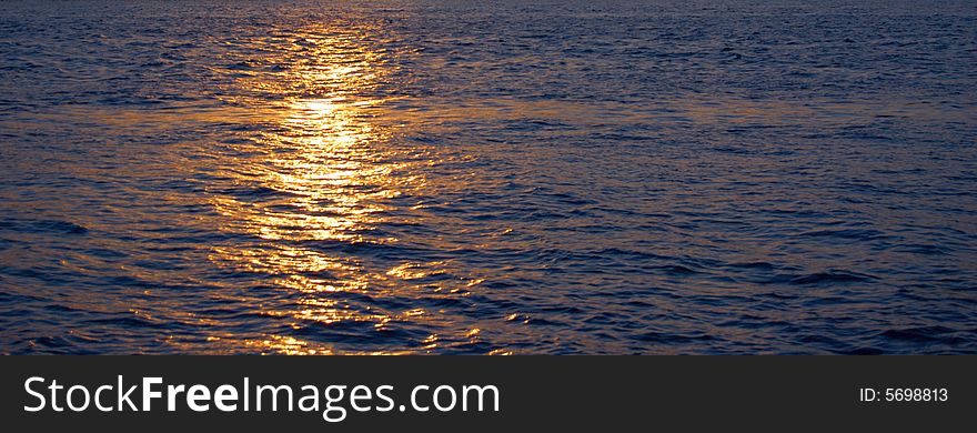 Ocean's sunset with gold sunbeam over water