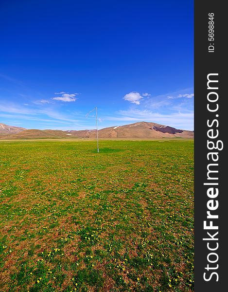A Mountain Landscape with vivid and pleasing spring colors. A flag is on the ground. A Mountain Landscape with vivid and pleasing spring colors. A flag is on the ground