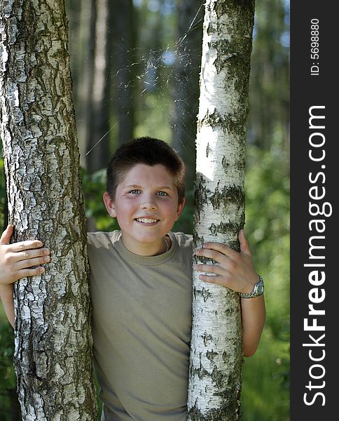 The smiling boy between two birches in Lithuanian forest. The smiling boy between two birches in Lithuanian forest.