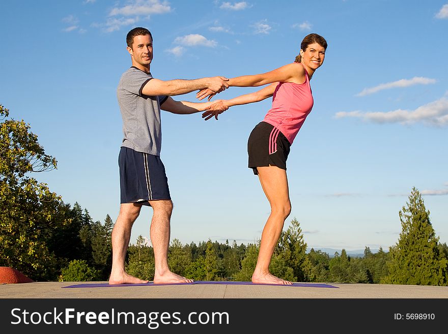 A woman, gets her arms stretched behind her back by a man, smiling. - horizontally framed. A woman, gets her arms stretched behind her back by a man, smiling. - horizontally framed