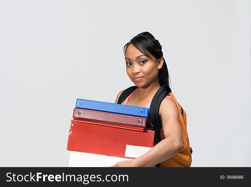 Female student wearing a backpack carries  notebooks and papers. Horizontally framed photograph. Female student wearing a backpack carries  notebooks and papers. Horizontally framed photograph.