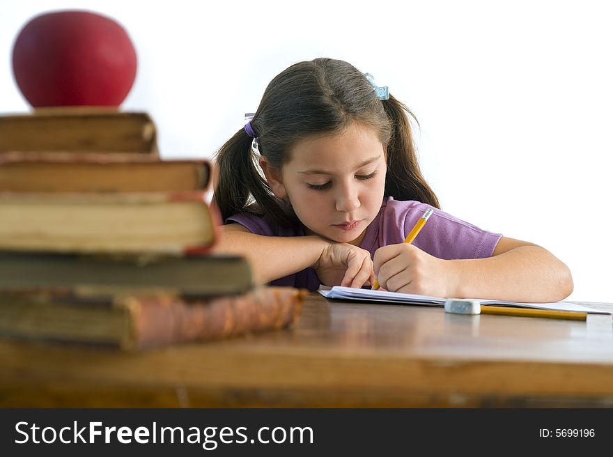 Girl pupil sitting by the table with globe and red apple on a pile of books, Isolated on white