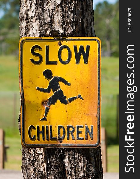 Old fashioned Slow Children street sign attached to a tree