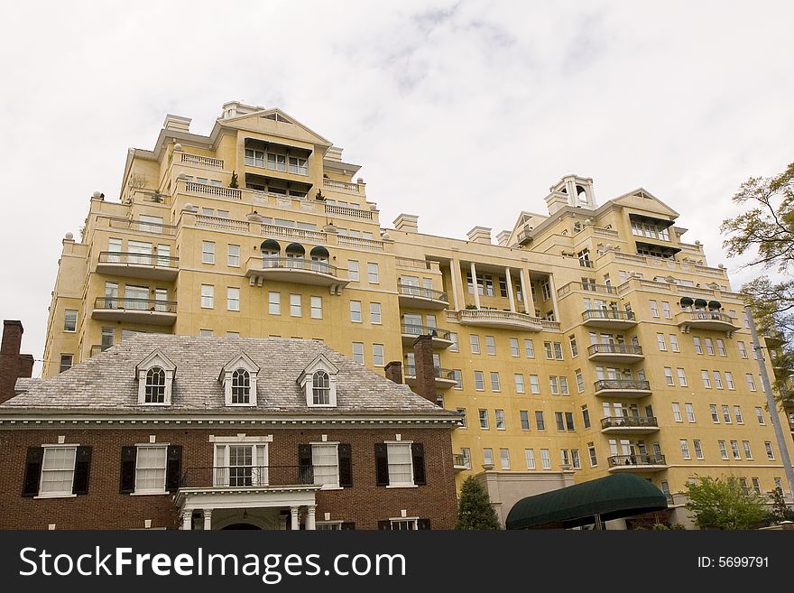 An old brick house in front of a modern yellow stucco condominium complex. An old brick house in front of a modern yellow stucco condominium complex