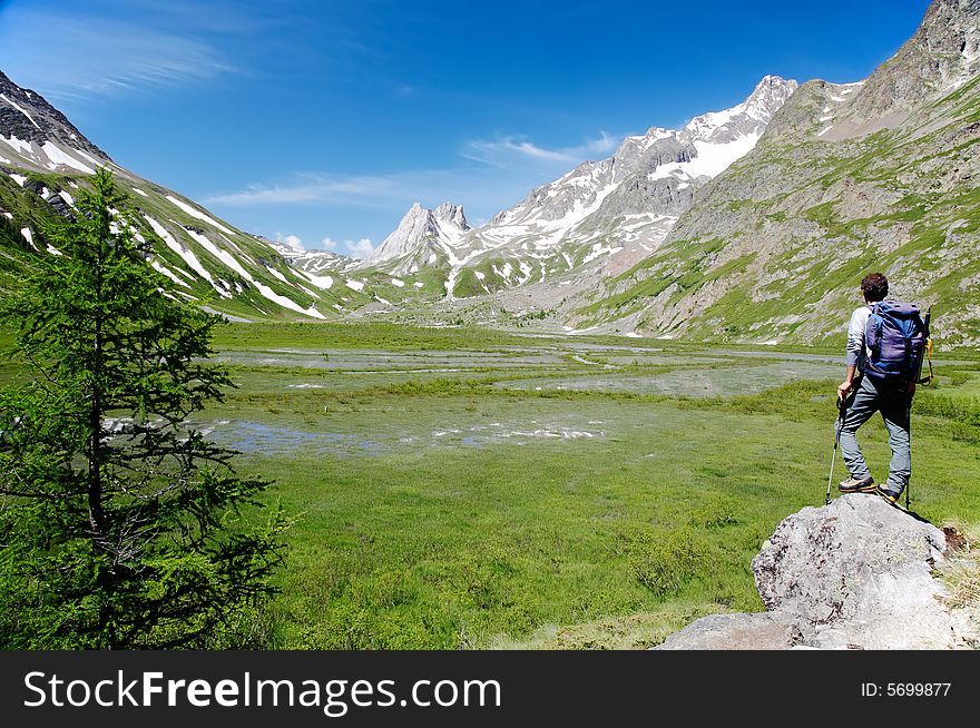 Male hiker enjoying the view over the beautiful landscape of Lac Combal, Val Veny, Courmayeur, Italy. Male hiker enjoying the view over the beautiful landscape of Lac Combal, Val Veny, Courmayeur, Italy
