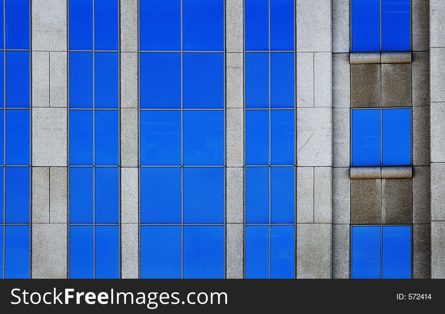 Windows reflecting blue sky and stone of office building create pattern. Windows reflecting blue sky and stone of office building create pattern