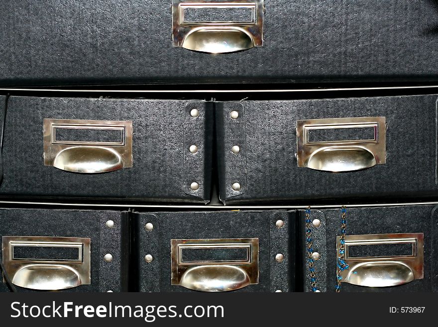 Black paper drawers with little necklace hanging out of right lower one. Black paper drawers with little necklace hanging out of right lower one