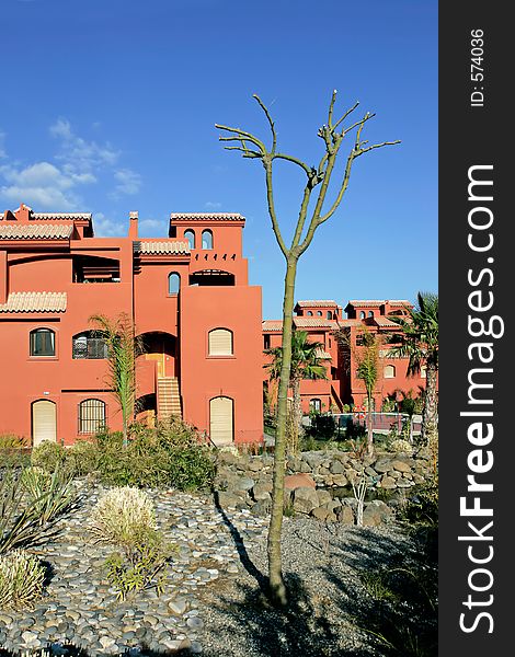Salmon or orange apartments on Spanish urbanization on the Costa del Sol in Spain with sunny blue sky. Salmon or orange apartments on Spanish urbanization on the Costa del Sol in Spain with sunny blue sky