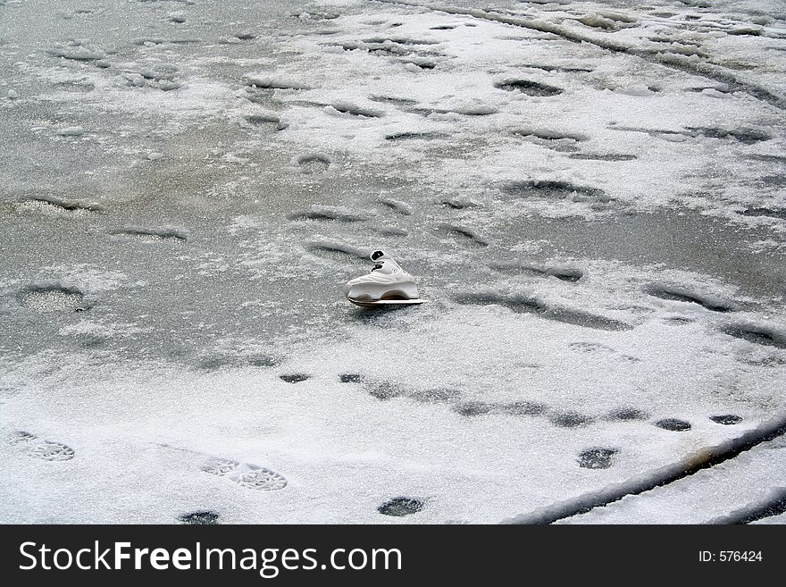 An abandoned white skating shoe in a frozen lagoon. An abandoned white skating shoe in a frozen lagoon.