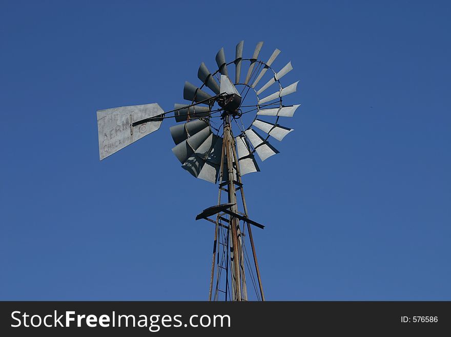 A rustic windmill set against a clear blue sky