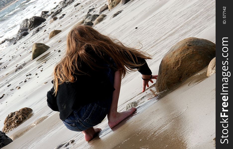 Young girl drawing in the wet sand at the beach. Young girl drawing in the wet sand at the beach
