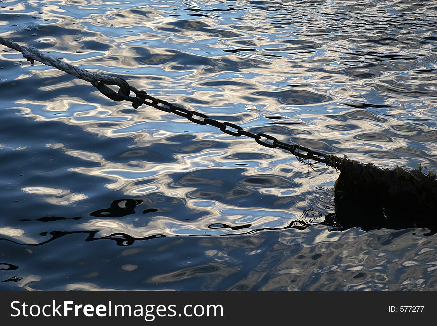 Boat chain silhouette against ocean water, seaweed tangled around the chain. Boat chain silhouette against ocean water, seaweed tangled around the chain