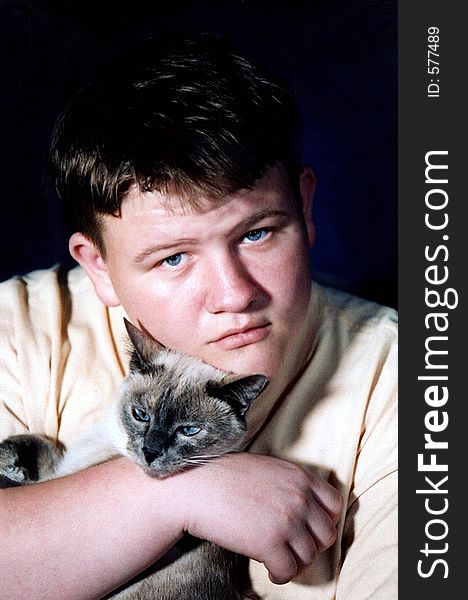 Teenage boy holding a Siamese cat. Teenage boy holding a Siamese cat.