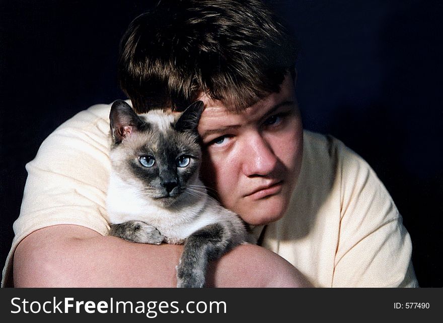 Teenage boy holding Siamese cat. Teenage boy holding Siamese cat.