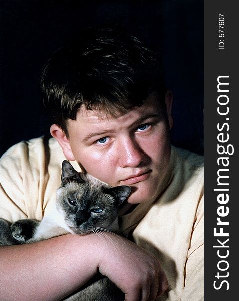 Teenage boy holding a Siamese cat. Teenage boy holding a Siamese cat.