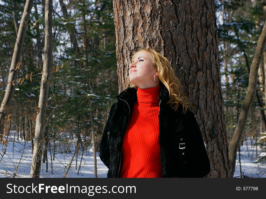 The young beautiful girl in a wood stands near a tree