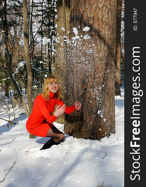 The young beautiful girl in a wood throws a snow