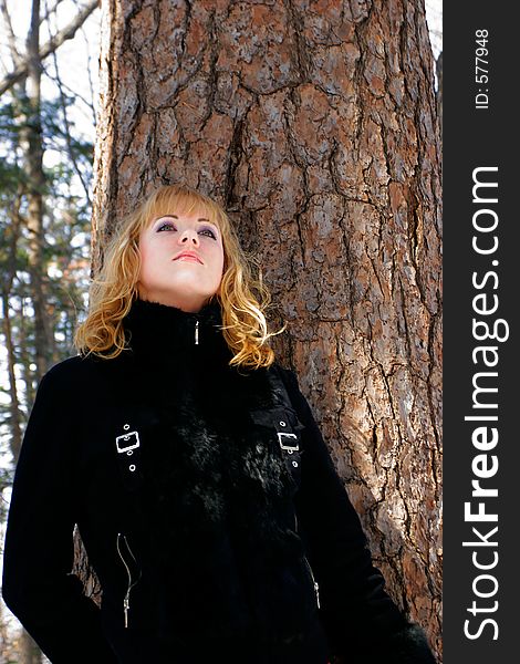 The young beautiful girl in a wood stands near a tree