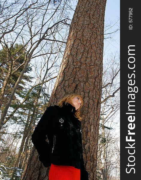 The young beautiful girl in a wood stands near a tree