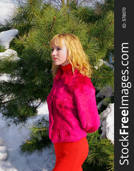 The young beautiful girl in a wood stands near a tree