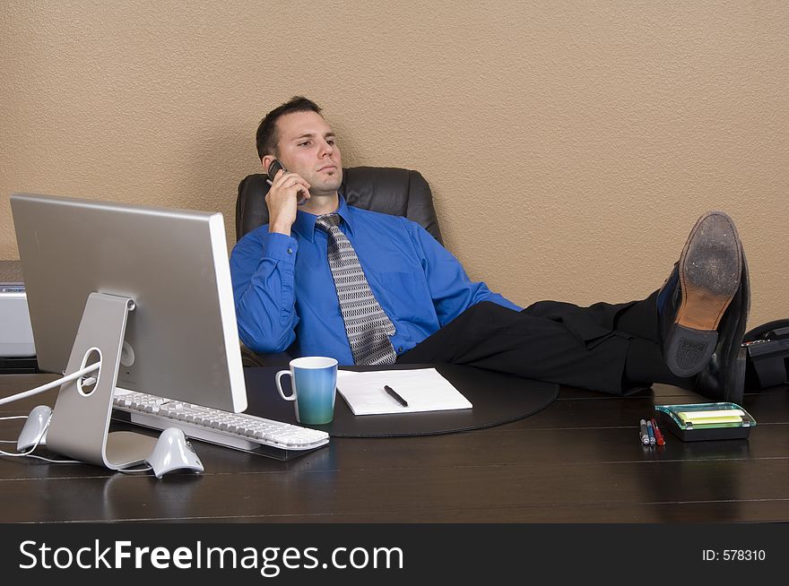 Young enthusiastic businessman on the phone in his office