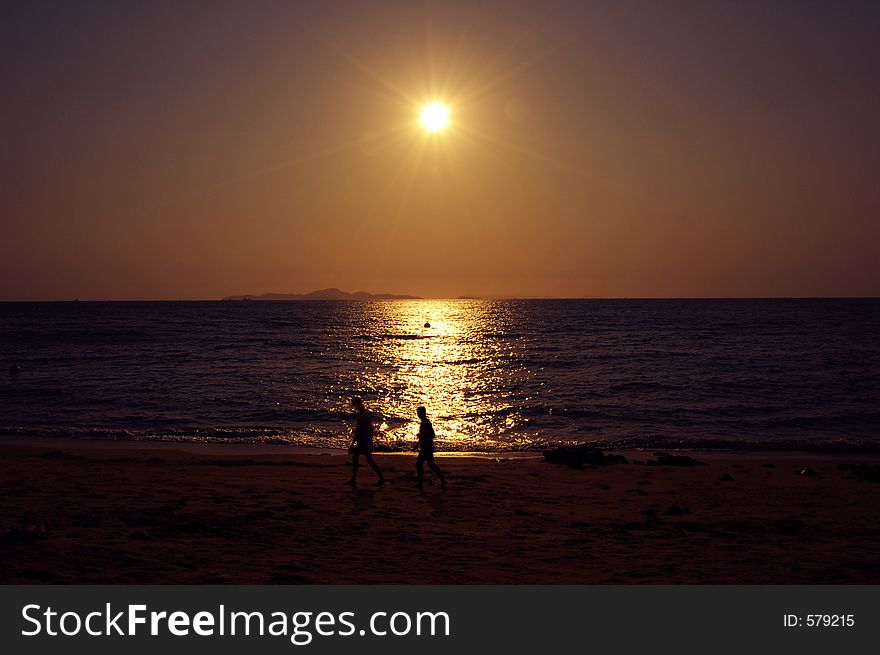 Two People walking agints sunset Location:Pattaya Beach, Thailand. Two People walking agints sunset Location:Pattaya Beach, Thailand