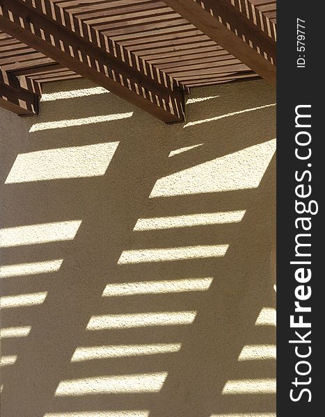 A slitted roof makes shadows on the wall outside