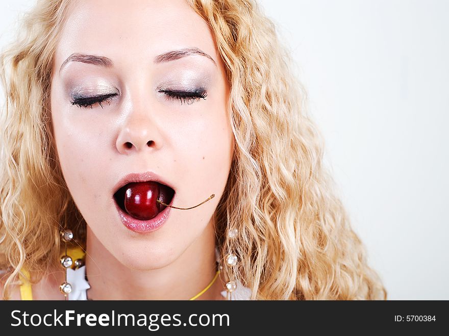 Beauty young woman with closed eyes and red cherry in mouth